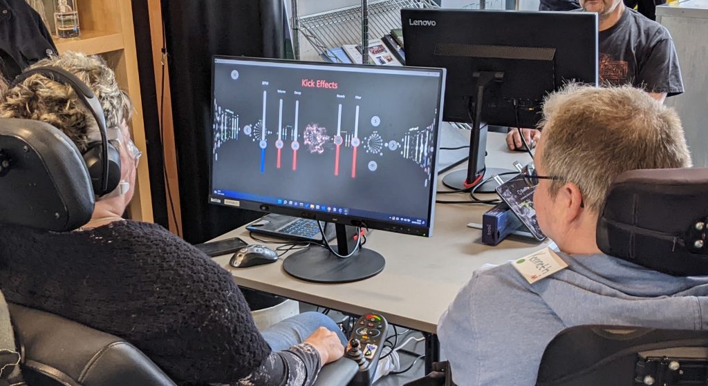 People living with ALS, in wheelchairs, looking at DuoRhythmo app on PC desktop display