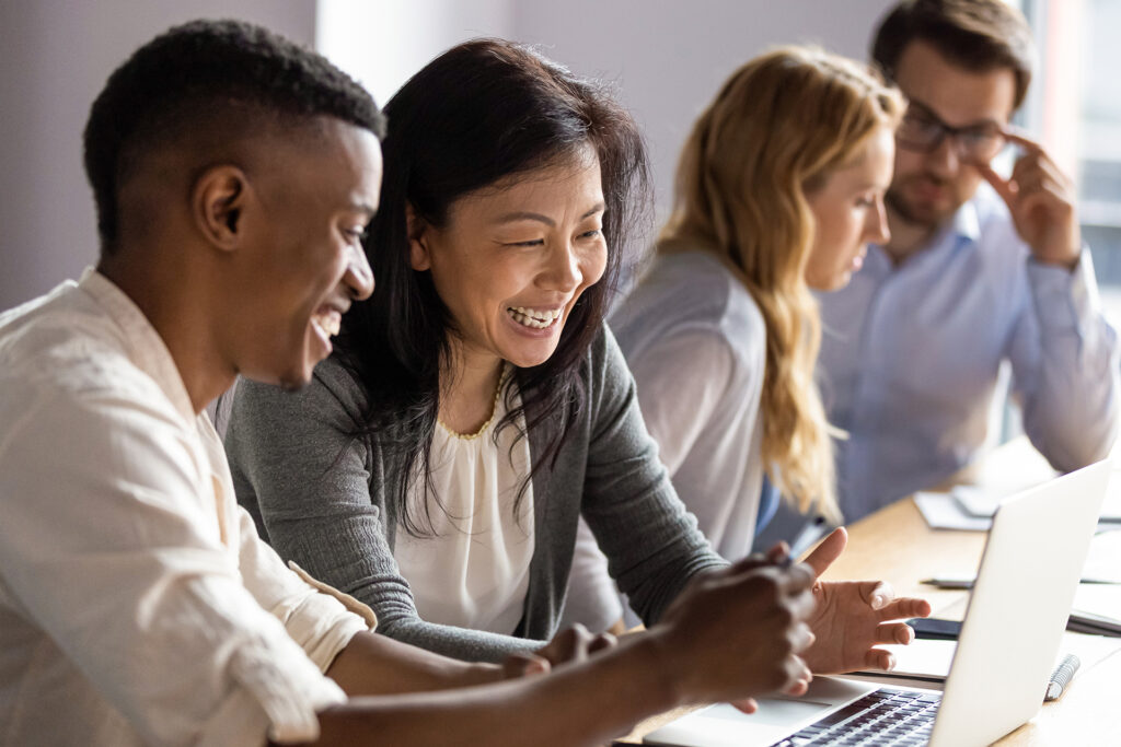 Four people in an office working together at computer devices.