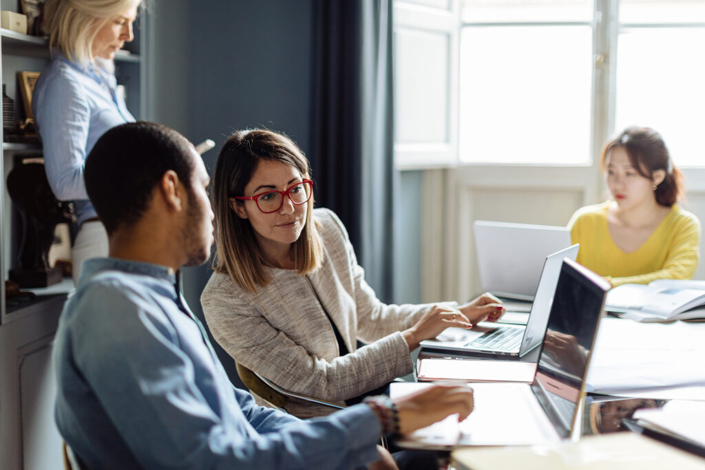 Four people in an office working on various devices.