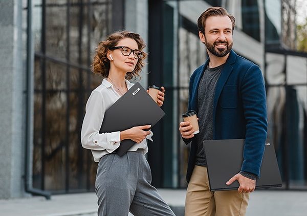 A man and woman outside holding laptops