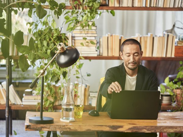 A man working on a laptop computer in an office with plants