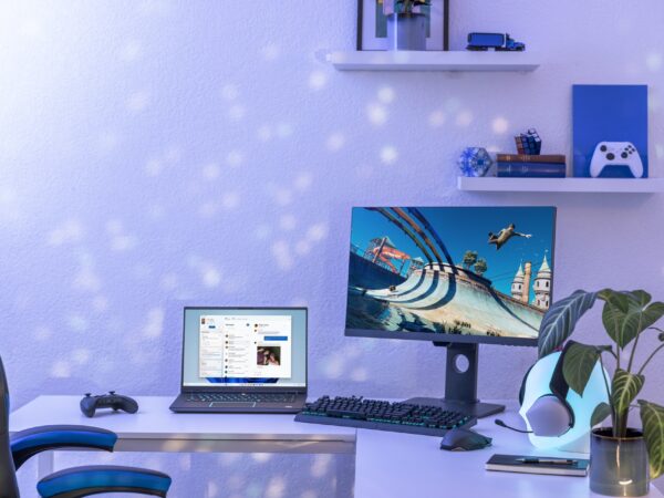 Desk in a home with a laptop computer, desktop PC and monitor, and Xbox controllers.