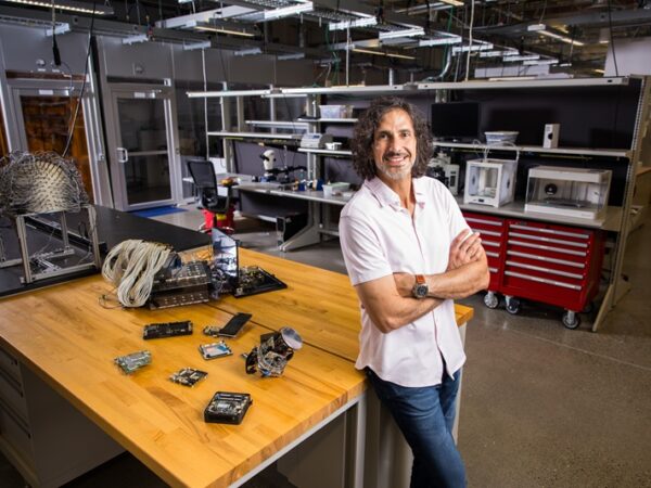 Man in a lab leaning against a table, arms crossed and smiling