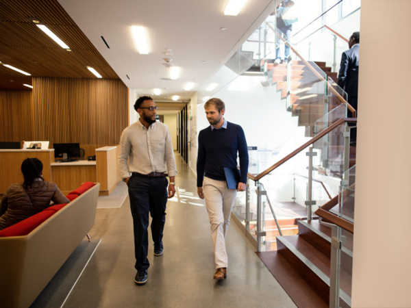 Sales manager meets informally while walking with IT pro to discuss software integration.