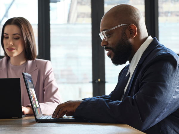 Woman and man working at laptop computers in a conference room.