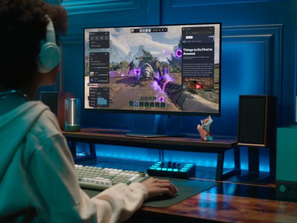 View from behind of a gamer wearing a headset and playing in front of a monitor.